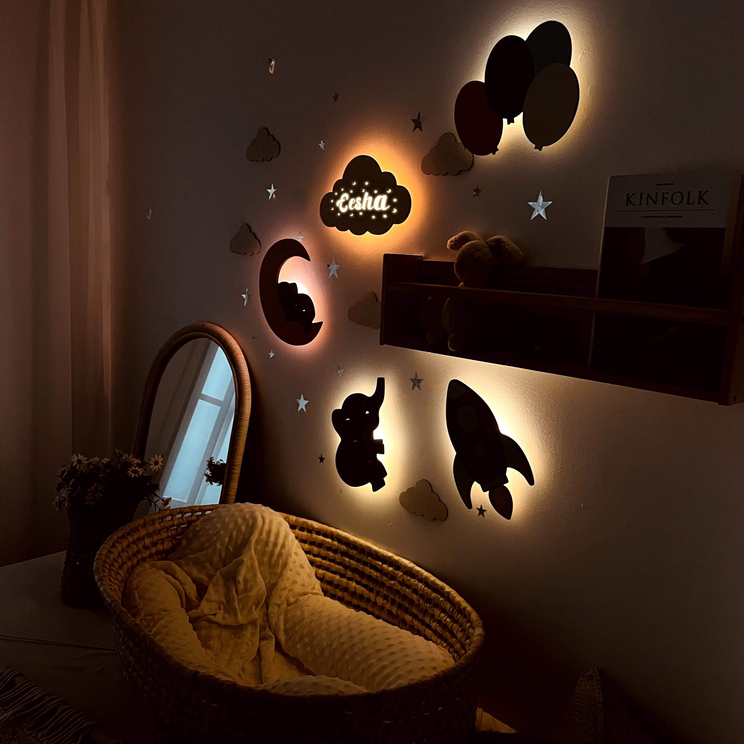 Personalized wooden wall lights with soft glow in a baby's room, featuring clouds, rockets, and balloons for a cozy atmosphere.