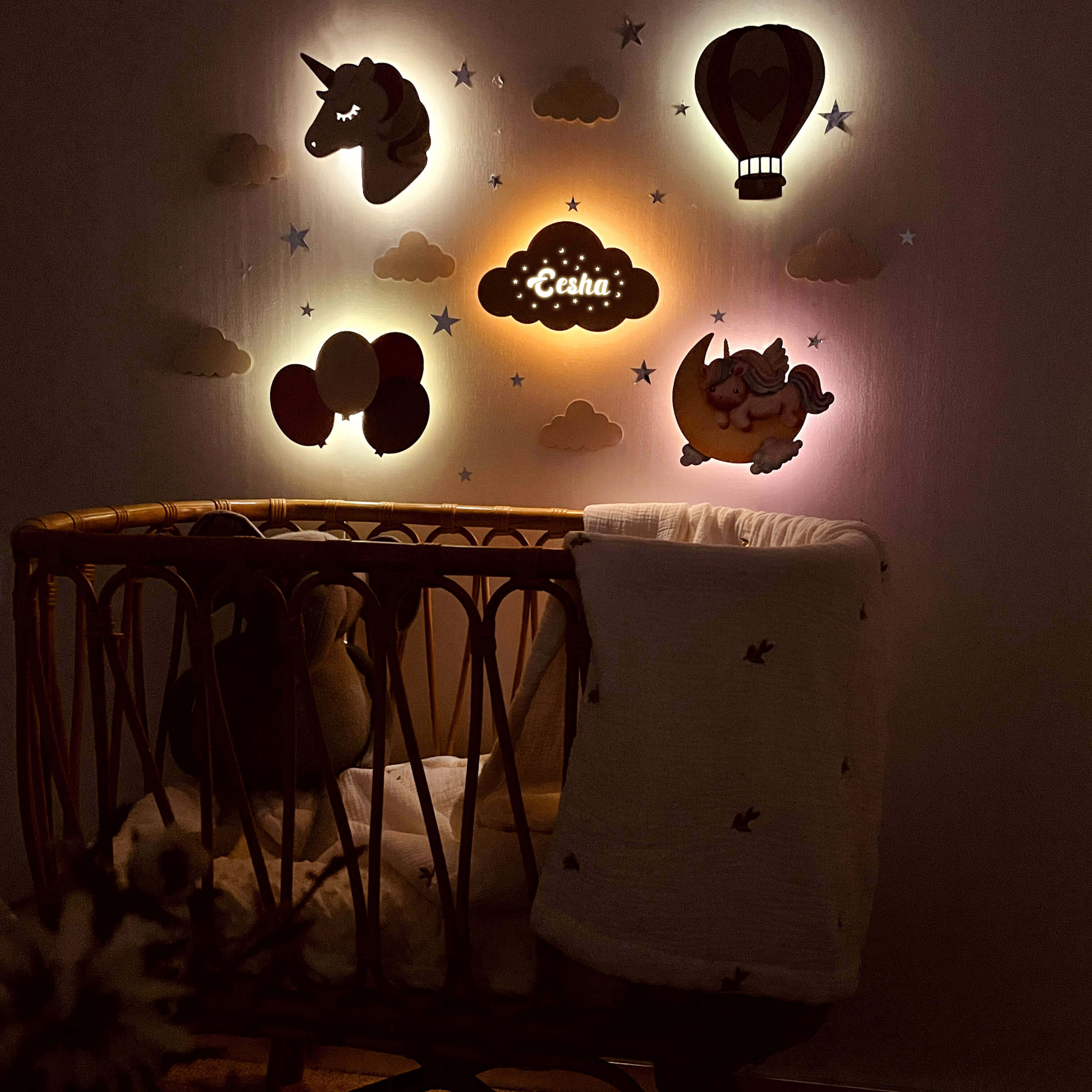 Personalized wooden baby room wall lights featuring unicorn, balloons, and clouds above a crib for a cozy ambiance.