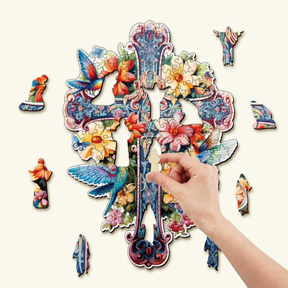 Hand holding a piece of the Blessing Cross-1 Wooden Jigsaw Puzzle featuring vibrant animal and flower designs.