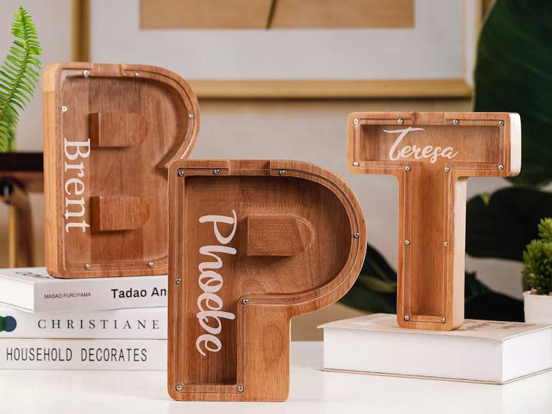 Personalised wooden letter piggy banks in a home setting, ideal gifts for kids to encourage saving.